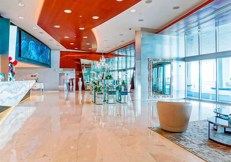 Grand lobby seating area at Jade Ocean in Sunny Isles Beach for the luxury and ultra luxury condos, with reflective columns, polished stone floors, designer seating, and glass entry doors.