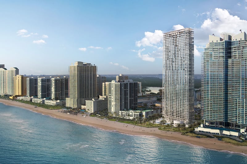 Jade Signature in Sunny Isles Beach luxury and ultra luxury condos aerial beachfront skyline view showing the tower along a sandy shoreline with neighboring high rises and bright blue water.
