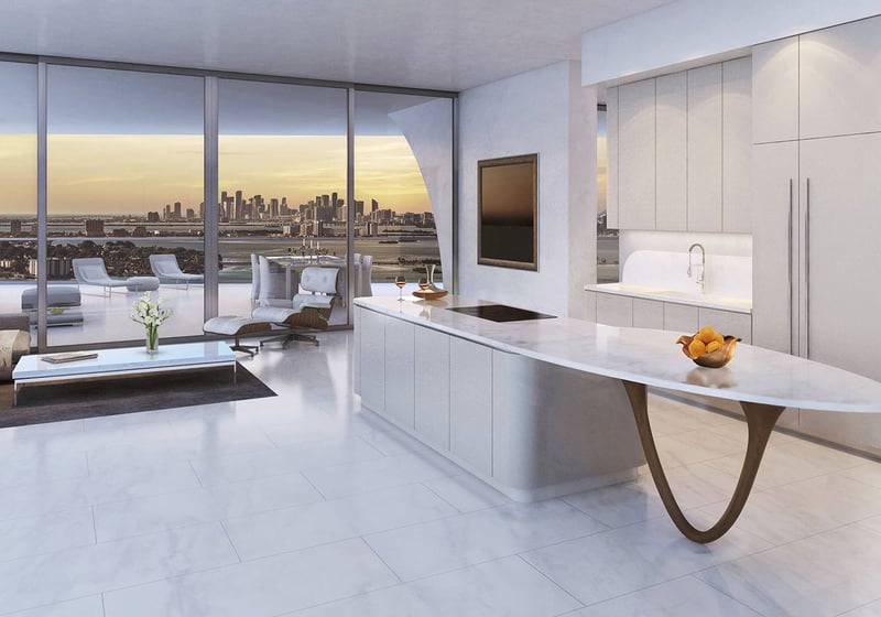Jade Signature in Sunny Isles Beach luxury and ultra luxury condos chef kitchen and living area with a marble island, sunset skyline view and a large terrace beyond the glass.