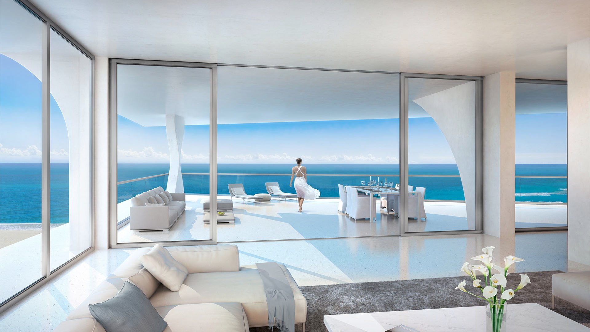 Jade Signature in Sunny Isles Beach luxury and ultra luxury condos living room opening to an expansive oceanfront terrace with lounge seating, dining table and wide water views.