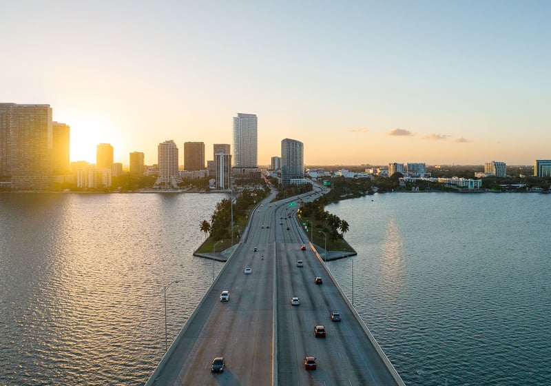 Jean-Georges Miami Tropic Residences sunrise aerial near the Biscayne Bay causeway and Miami skyline, Miami, Florida, representing luxury and ultra luxury preconstruction condos in a prime waterfront location.