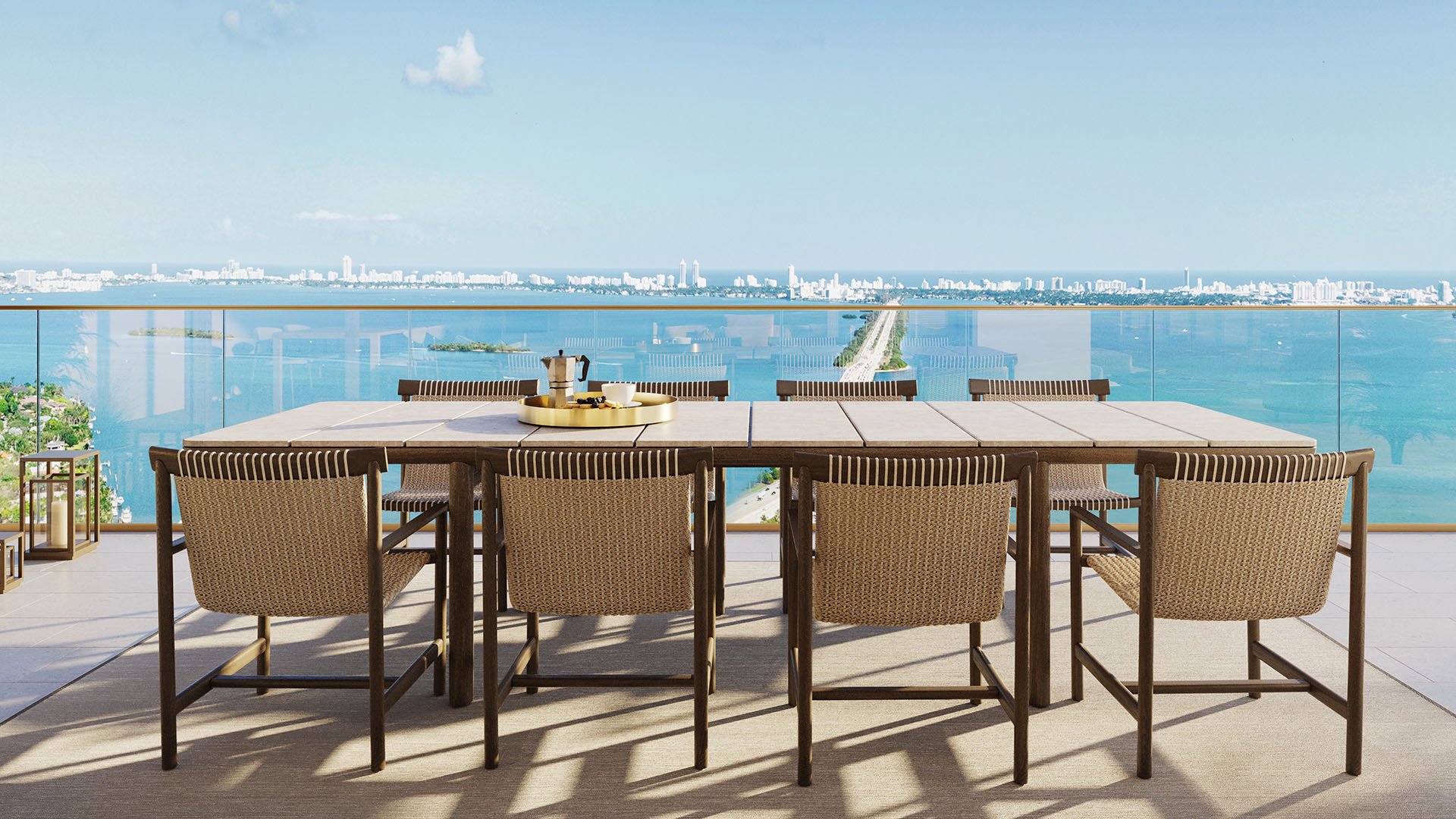Outdoor terrace dining at Jean-Georges Miami Tropic Residences with Biscayne Bay causeway views, Miami, Florida, featuring alfresco table and skyline panorama, promoting luxury and ultra luxury preconstruction condos lifestyle.