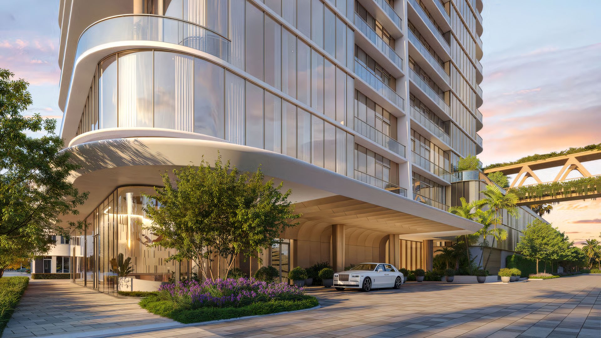 Kempinski Residences Miami in Miami Design District, luxury and ultra luxury condos, preconstruction arrival scene with a sweeping porte cochere, glass lobby, landscaped entry, and an elevated garden bridge beside the tower.