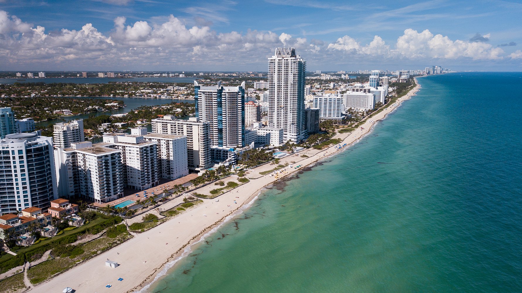 Miami Beach skyline aerial with oceanfront towers and Biscayne Bay, iconic strip for luxury and ultra luxury condos; preconstruction and resale inventory. Featuring view.