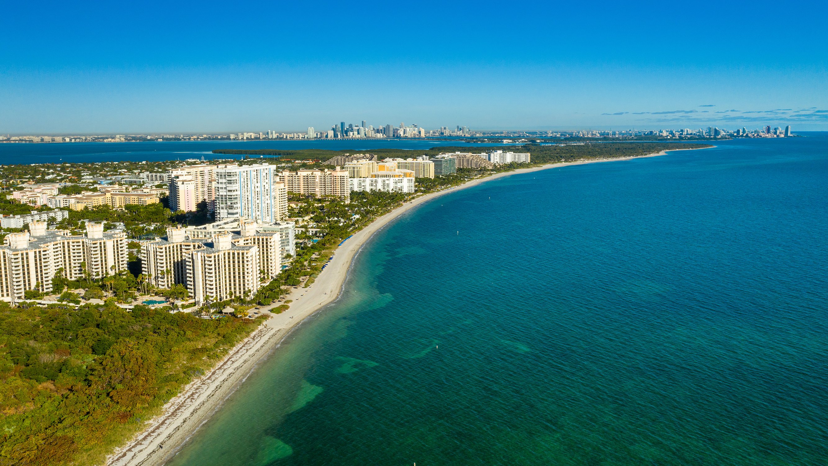Miami coastline aerial, turquoise Atlantic, sandy beaches and bayside towers; major South Florida hub for luxury and ultra luxury condos, preconstruction and resale. Featuring view.