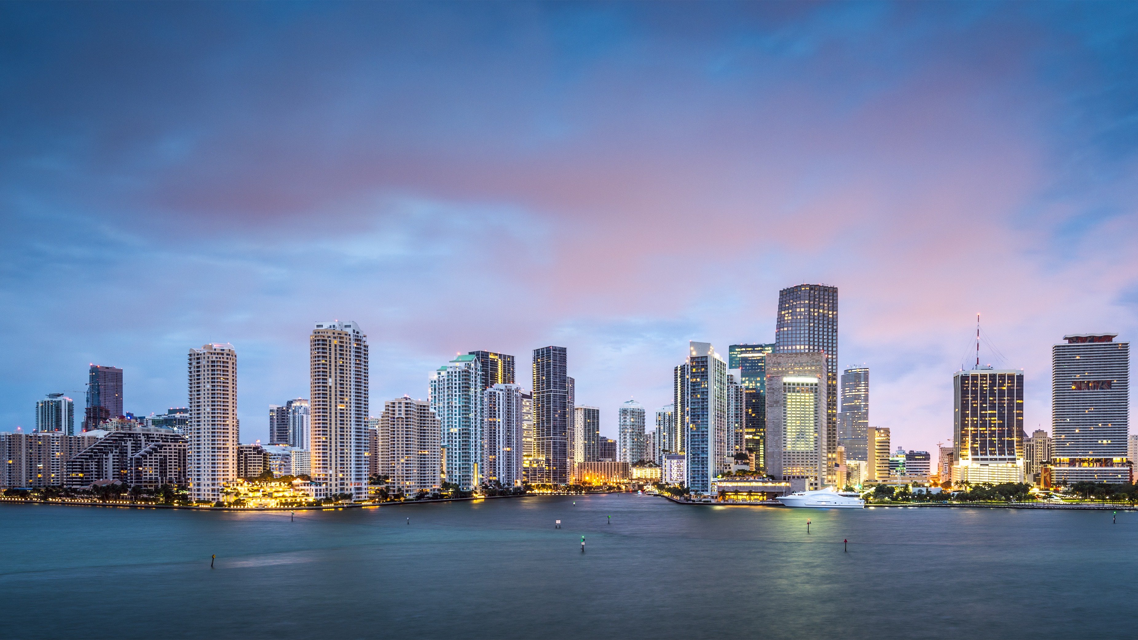 Miami skyline at dusk with glowing towers and bay reflections—Downtown Miami; sought‑after location for luxury and ultra luxury condos, offering preconstruction and resale.