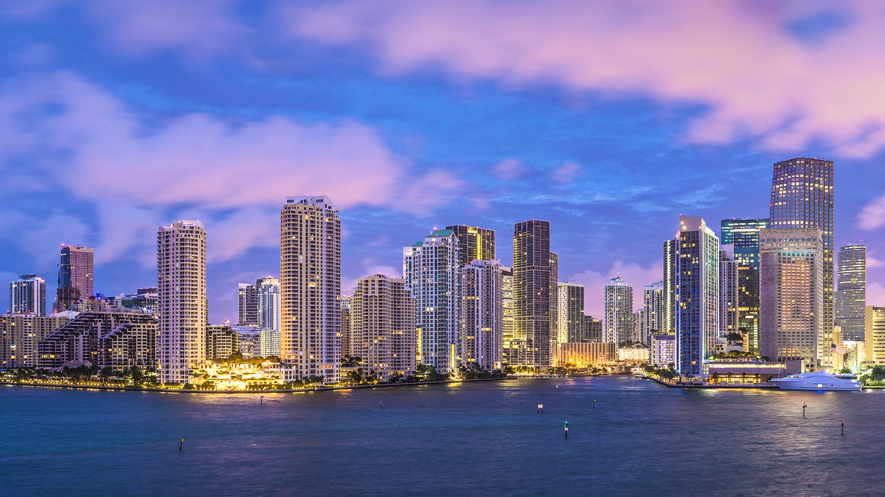 Miami skyline at sunset with pastel clouds and bay—Downtown Miami; coveted urban coast for luxury and ultra luxury condos, with preconstruction and resale.