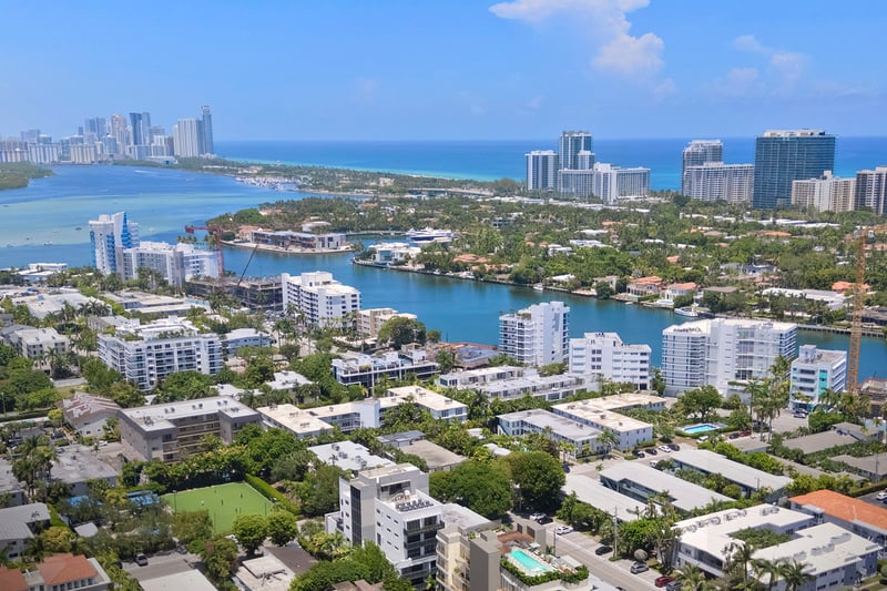 Mila Bay Harbor Islands preconstruction luxury and ultra luxury condos in Bay Harbor Islands with an aerial view over the waterfront neighborhood, bay, and ocean beyond nearby residences and waterways.
