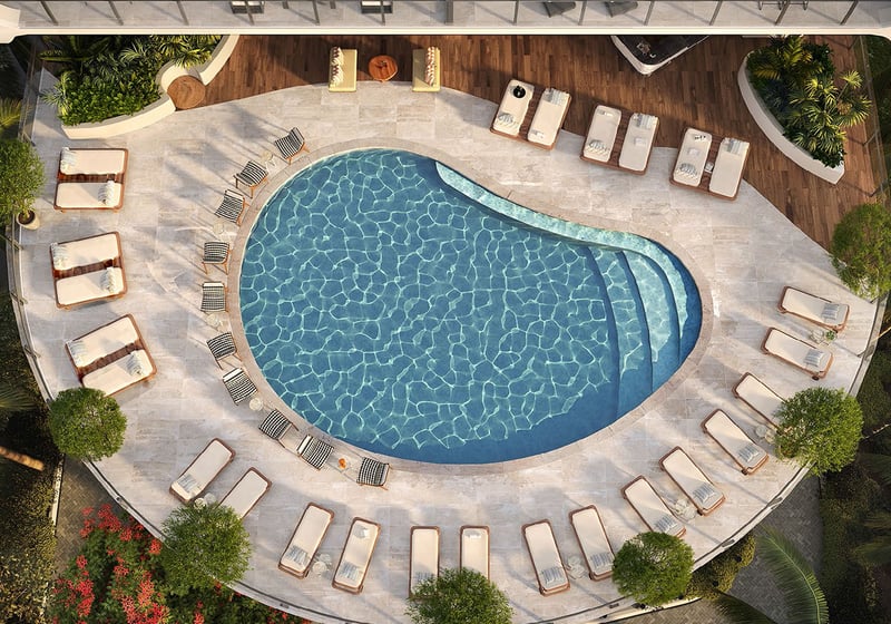 Aerial view of the pool terrace with loungers surrounding the water at Mr C Residences Bayshore Tower in Coconut Grove, showcasing luxury, ultra luxury condos with a resort style outdoor amenity terrace.