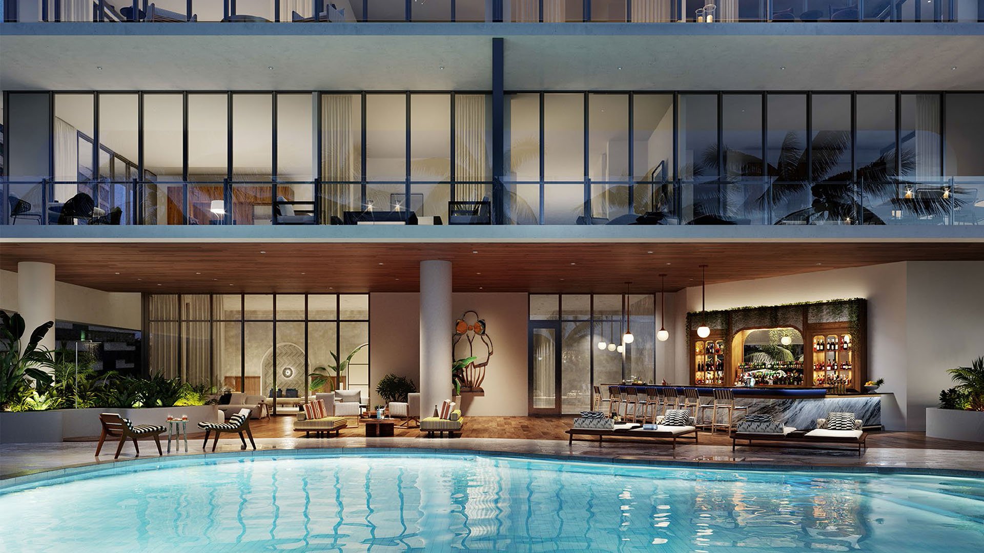 Nighttime pool courtyard with lounge seating, illuminated water, and a bar backdrop at Mr C Residences Bayshore Tower in Coconut Grove, showcasing luxury, ultra luxury condos with resort style evening amenities.