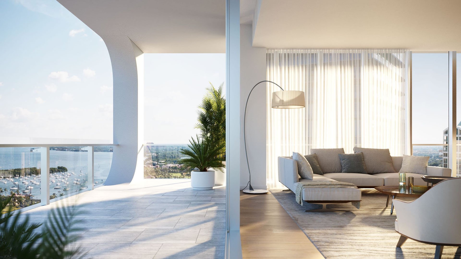Living room opening to a curved balcony with marina and bay views at Mr C Residences Bayshore Tower in Coconut Grove, showcasing luxury, ultra luxury condos with indoor outdoor waterfront lounge space.