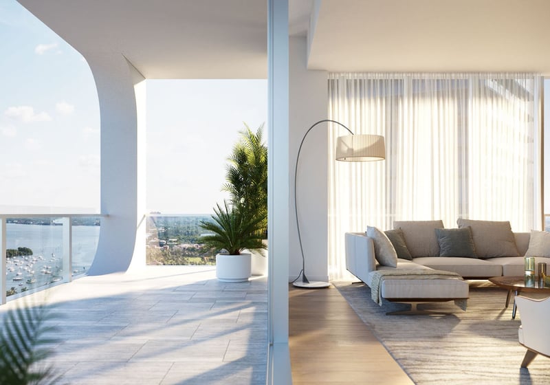 Living room opening to a curved balcony with marina and bay views at Mr C Residences Bayshore Tower in Coconut Grove, showcasing luxury, ultra luxury condos with indoor outdoor waterfront lounge space.
