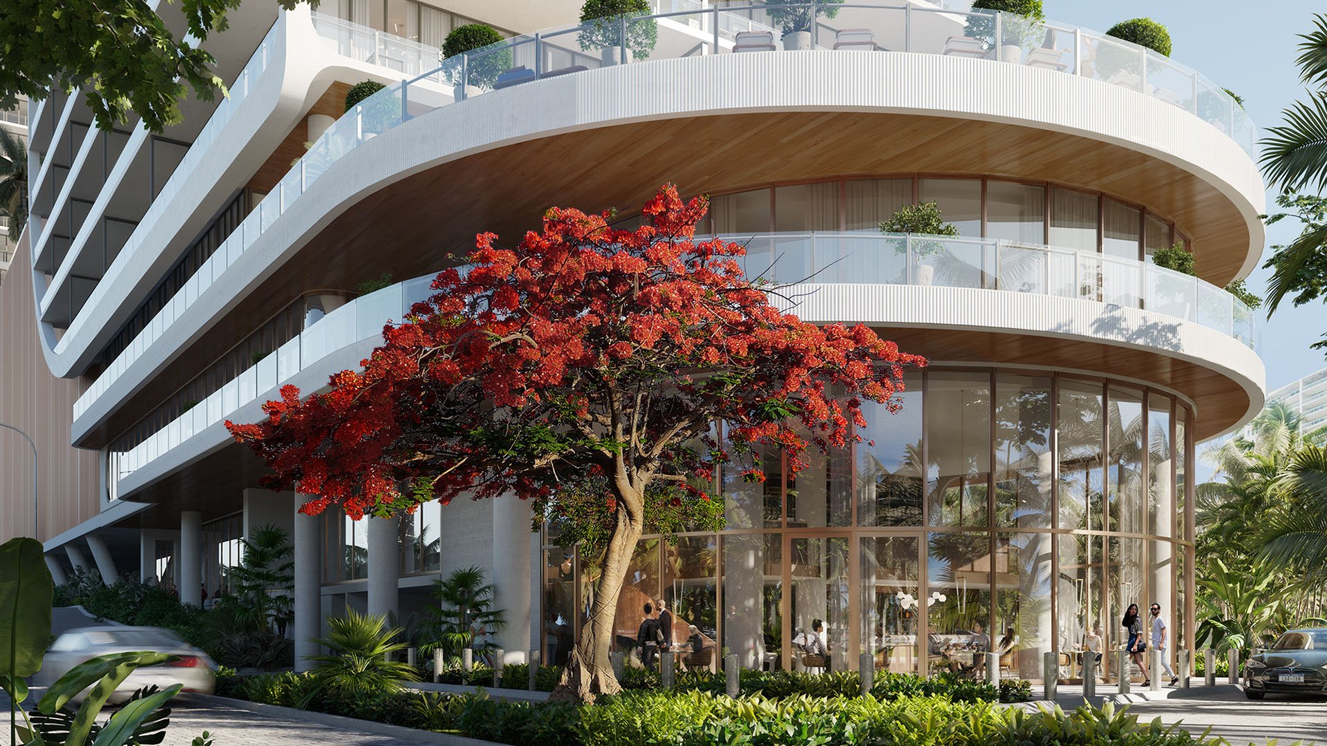 Curved condo exterior with rounded terraces, glass walls, and a red flowering tree at street level at Mr C Residences Bayshore Tower in Coconut Grove, presenting luxury, ultra luxury condos with sculptural architecture.