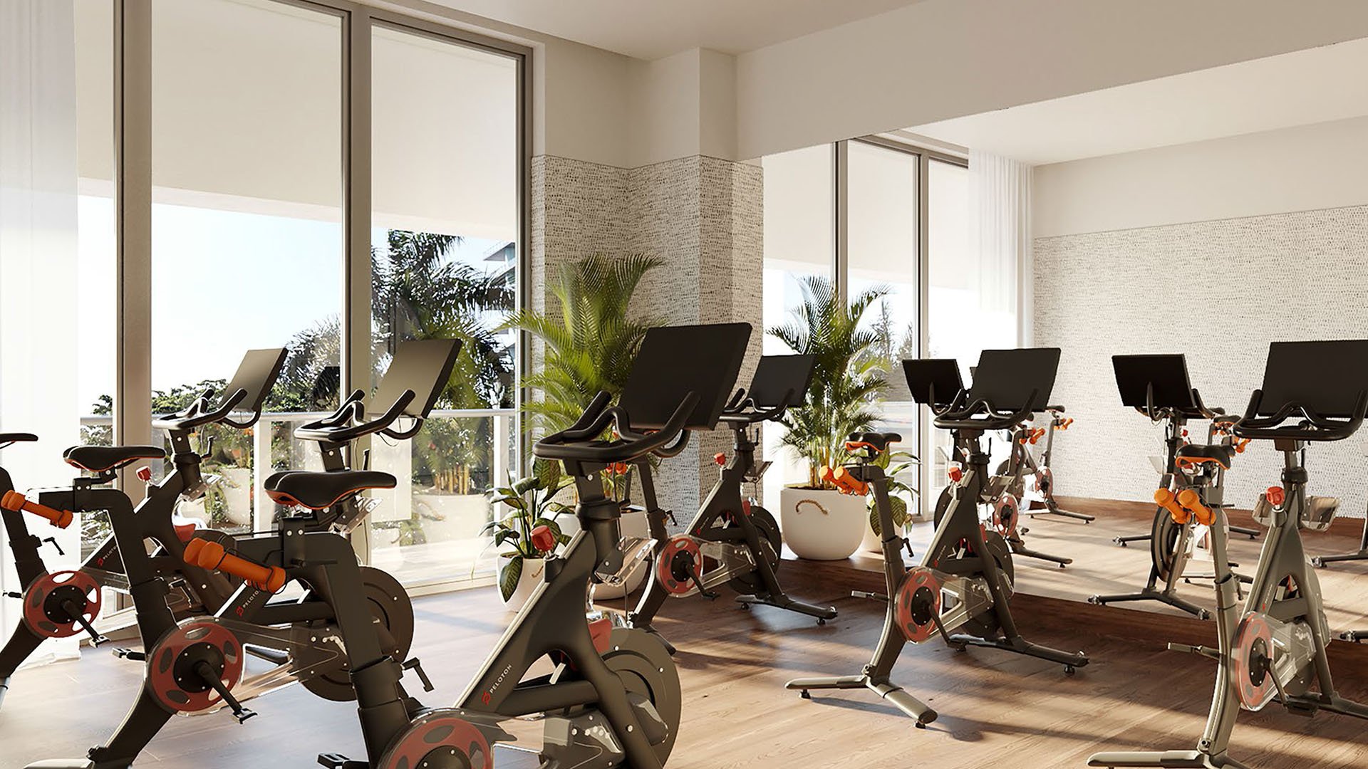 Fitness studio with stationary bikes, lounge chairs, and garden facing windows at Mr C Residences Bayshore Tower in Coconut Grove, showcasing luxury, ultra luxury condos with wellness focused amenity space.