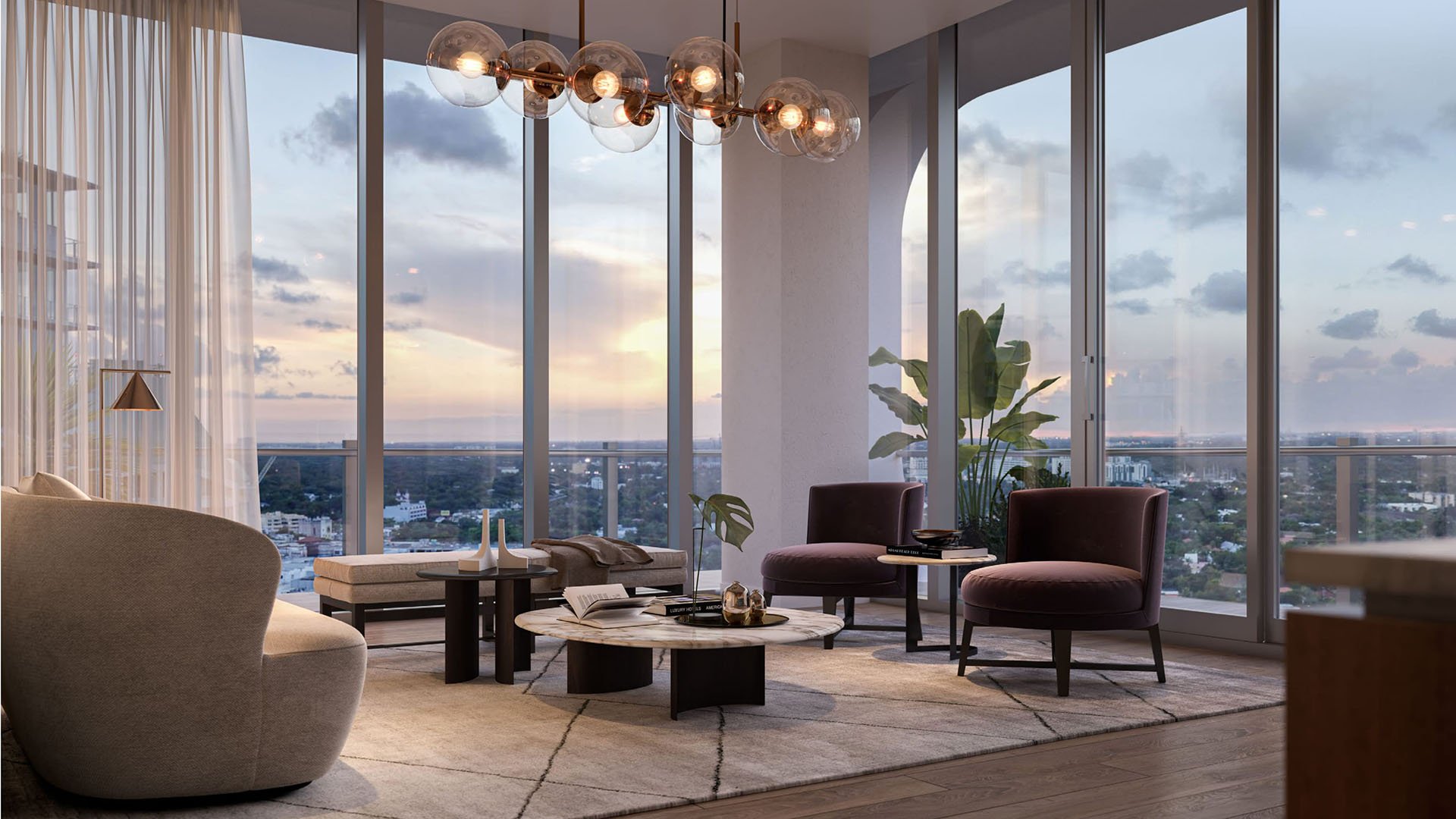 Corner living room with sunset skyline views, floor-to-ceiling glass, and sculptural lounge seating at Mr C Residences Bayshore Tower in Coconut Grove, featuring luxury, ultra luxury condos with refined entertaining space.