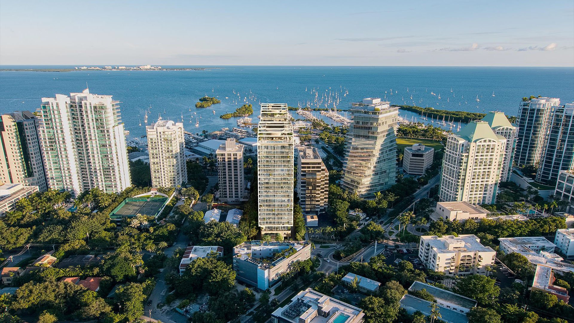 Aerial view of Mr. C Residences Tigertail Tower, Coconut Grove, with Biscayne Bay, marina slips and surrounding high-rises, showcasing luxury and ultra luxury condos in a waterfront setting.