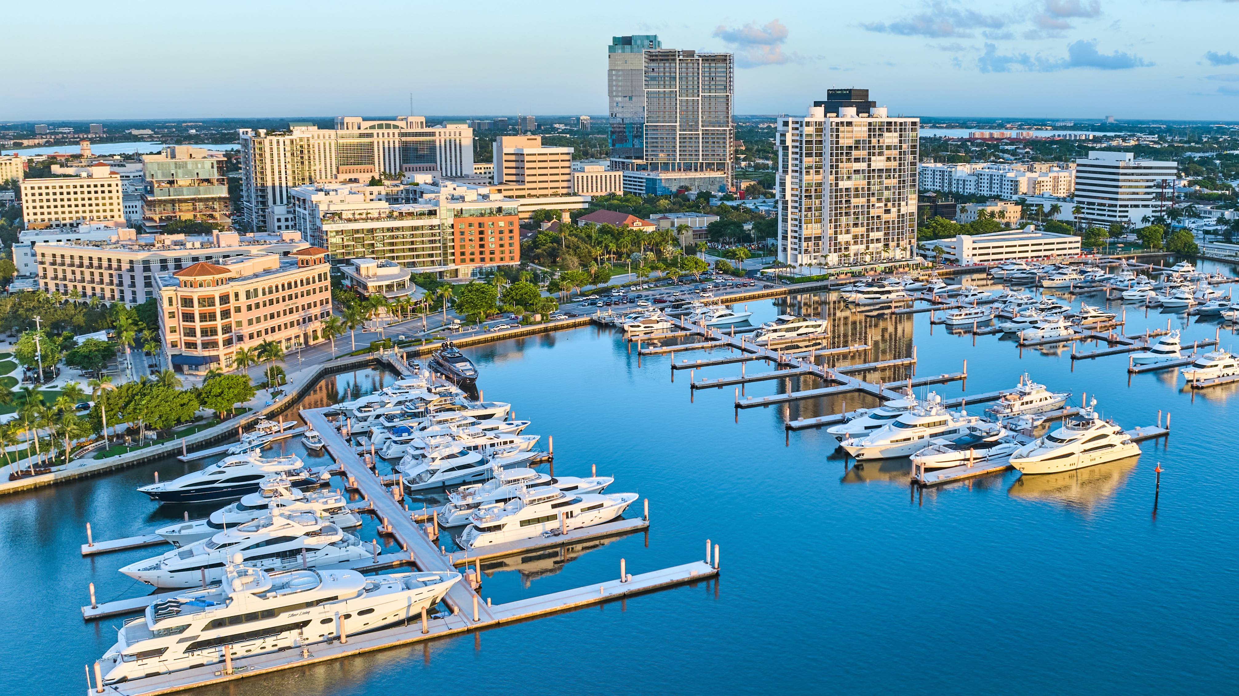 Mr. C Residences West Palm Beach marina at sunset with yachts and skyline views, highlighting luxury and ultra luxury preconstruction condos. Featuring city.