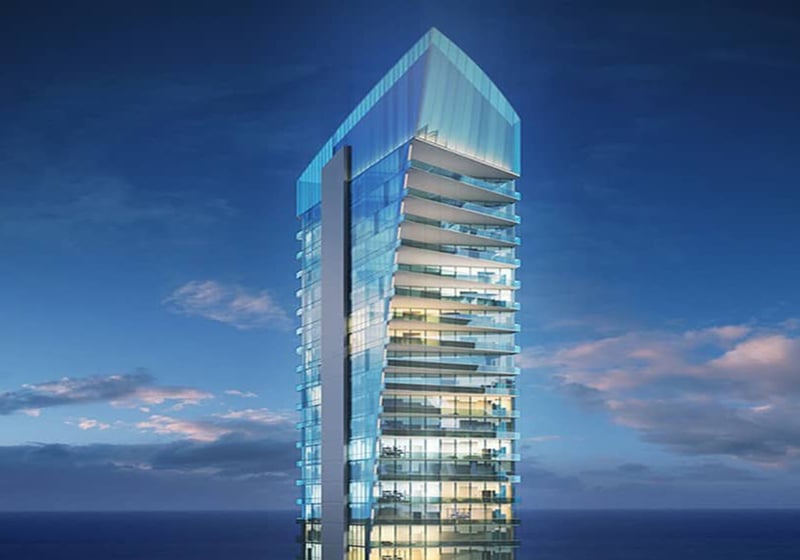Illuminated glass tower at blue hour at Muse Residences in Sunny Isles Beach, showcasing the striking architecture of luxury and ultra luxury oceanfront condos.