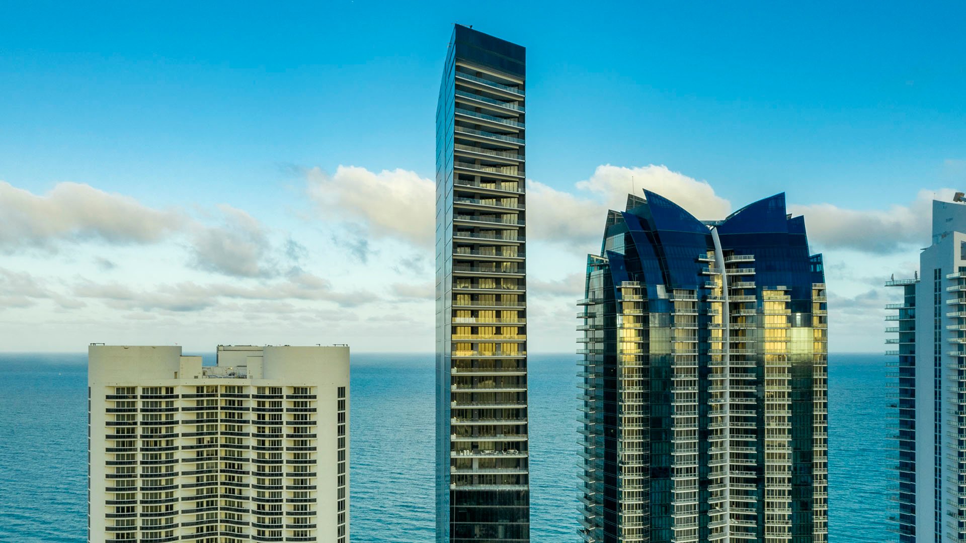 Oceanfront tower view at Muse Residences in Sunny Isles Beach beside neighboring high-rises and the Atlantic horizon, highlighting luxury and ultra luxury condos.