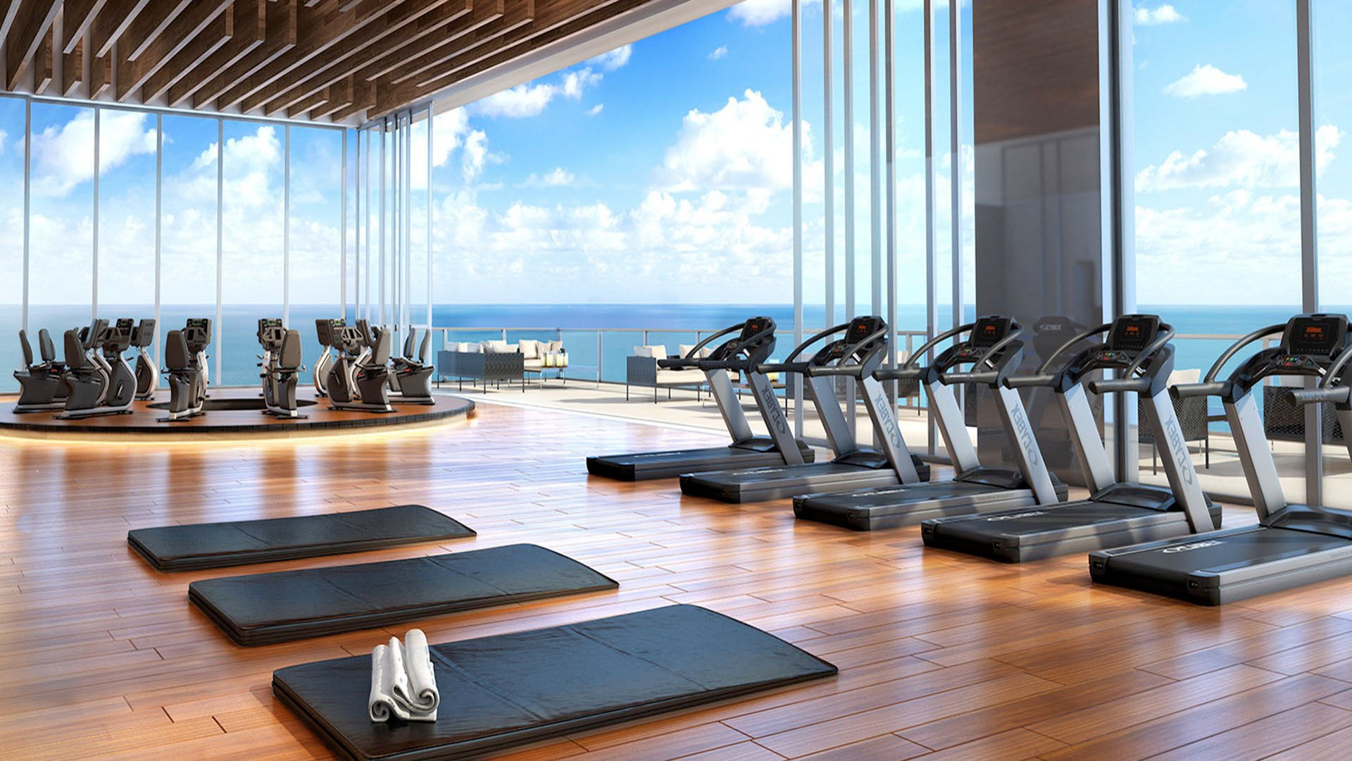 Oceanview fitness center with treadmills, yoga mats, and floor-to-ceiling glass at Muse Residences in Sunny Isles Beach, serving luxury and ultra luxury condos.