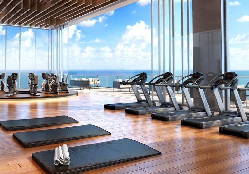 Oceanview fitness center with treadmills, yoga mats, and floor-to-ceiling glass at Muse Residences in Sunny Isles Beach, serving luxury and ultra luxury condos.