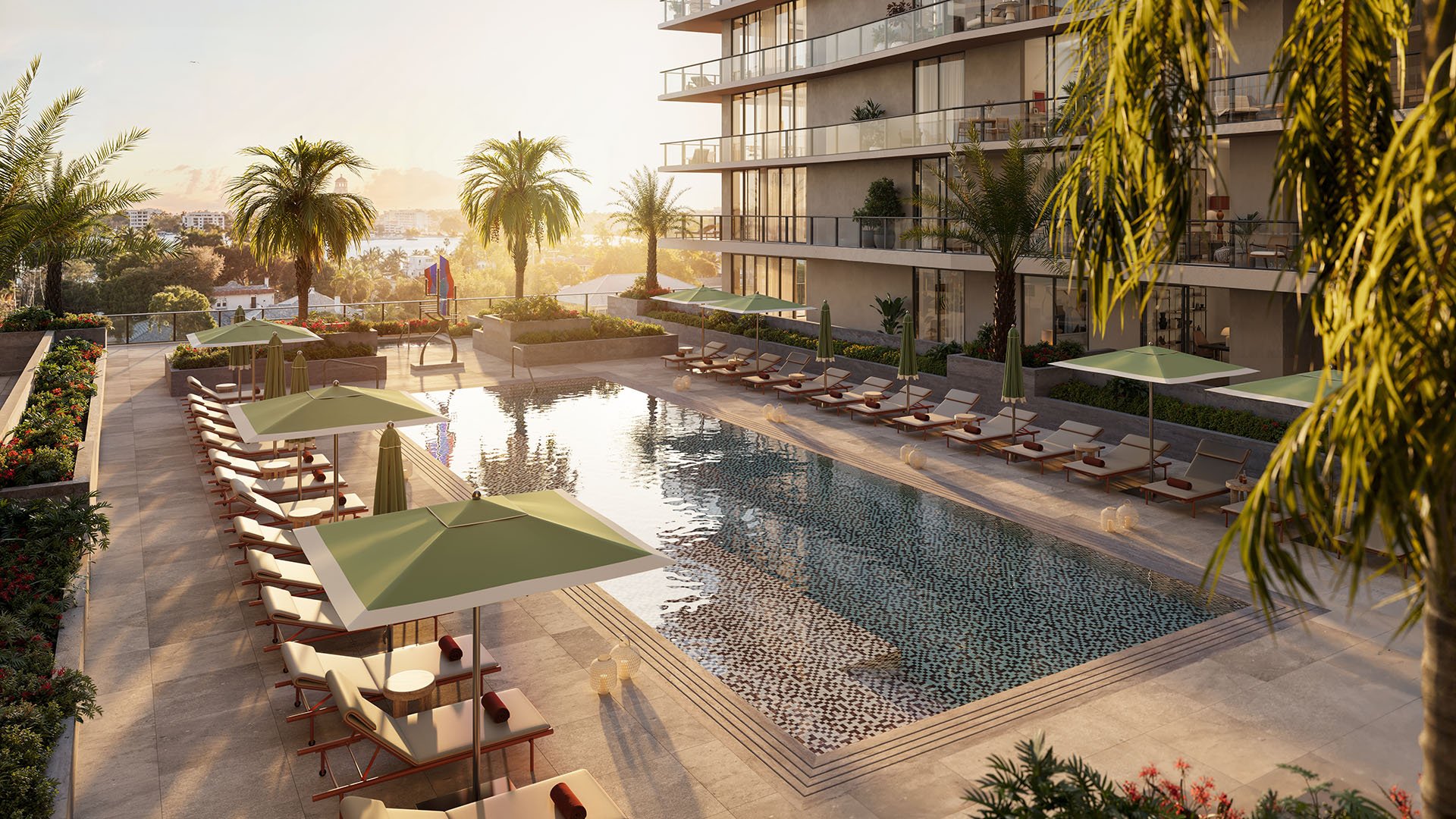 Elevated amenity pool deck at Nora House in West Palm Beach, luxury and ultra luxury condos featuring a large courtyard pool, green umbrellas, sun loungers, tropical planting, and glass-railed balconies in warm light.