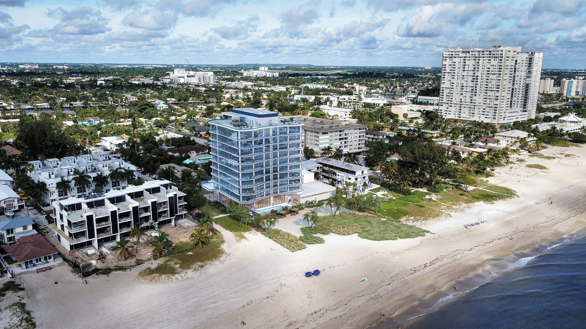 Aerial view of Ocean 580 in Pompano Beach, preconstruction luxury and ultra luxury condos showing the oceanfront tower, broad beach, surrounding neighborhood and nearby waterfront high-rises.