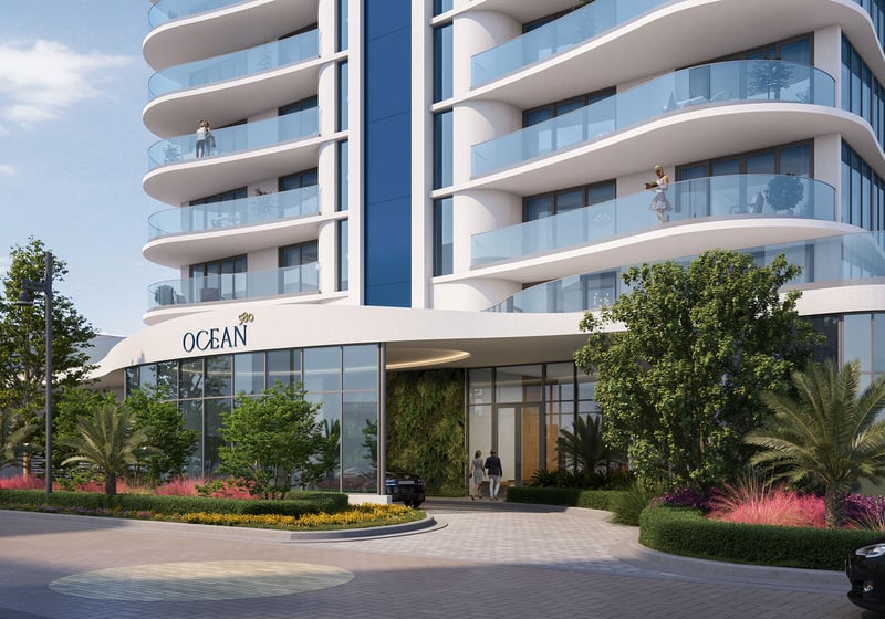 Daytime entrance at Ocean 580 in Pompano Beach, preconstruction luxury and ultra luxury condos with curved glass balconies, a porte cochere driveway, landscaped planting beds and a modern lobby frontage.