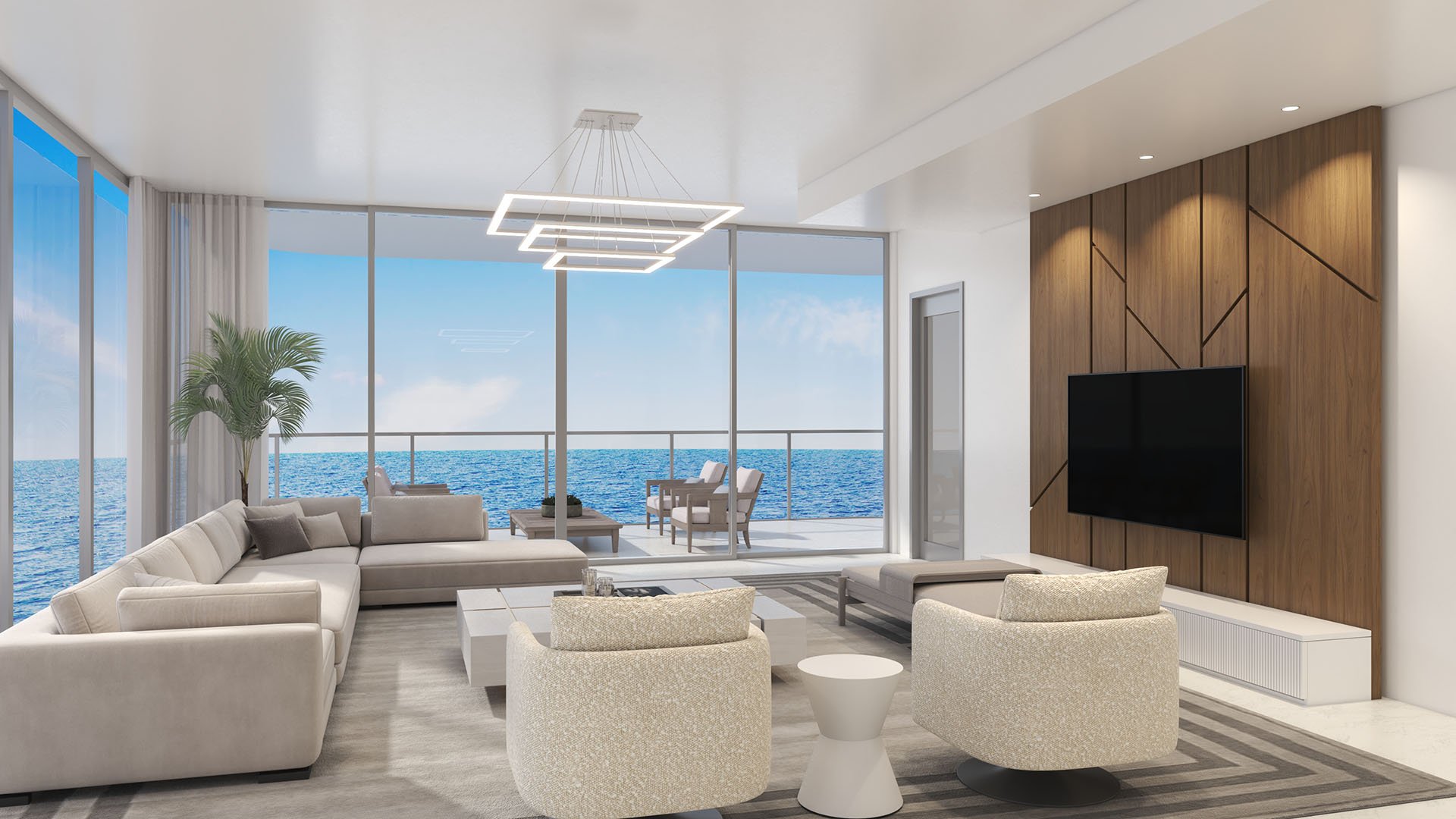 Oceanfront living room at Ocean 580 in Pompano Beach, preconstruction luxury and ultra luxury condos with floor-to-ceiling glass, a wide balcony, sectional seating and a wood media wall facing the water.