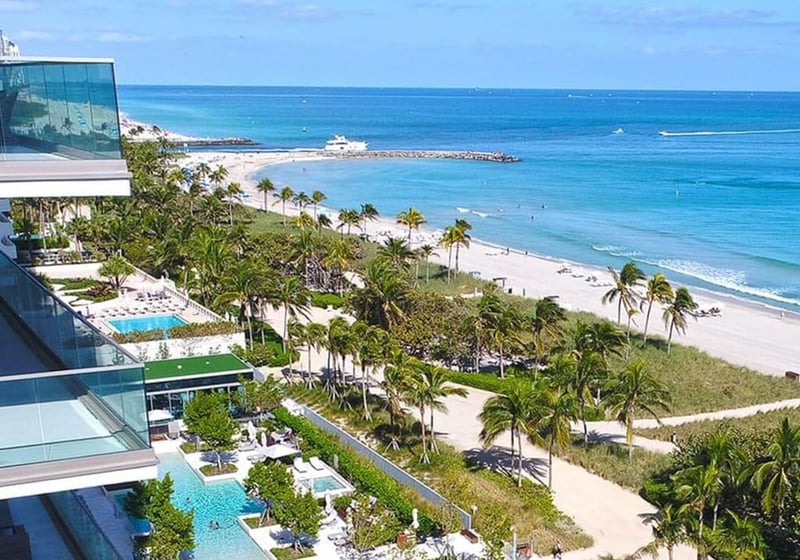Aerial waterfront view of beachfront pools, landscaped grounds and the shoreline at Oceana Bal Harbour in Bal Harbour, Florida, highlighting the luxury oceanfront setting of these ultra luxury condos.