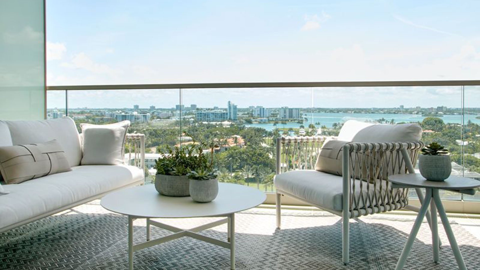 Balcony seating area with cushioned lounge furniture and a wide bay skyline view at Oceana Bal Harbour in Bal Harbour, Florida, reflecting the luxury indoor outdoor lifestyle of these ultra luxury condos.