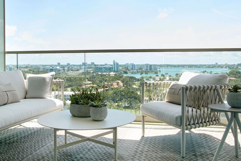 Balcony seating area with cushioned lounge furniture and a wide bay skyline view at Oceana Bal Harbour in Bal Harbour, Florida, reflecting the luxury indoor outdoor lifestyle of these ultra luxury condos.