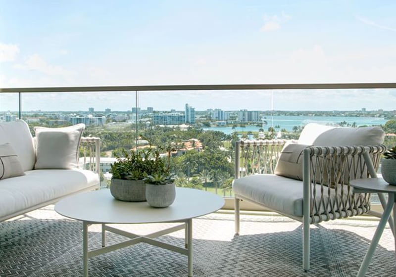 Balcony seating area with cushioned lounge furniture and a wide bay skyline view at Oceana Bal Harbour in Bal Harbour, Florida, reflecting the luxury indoor outdoor lifestyle of these ultra luxury condos.