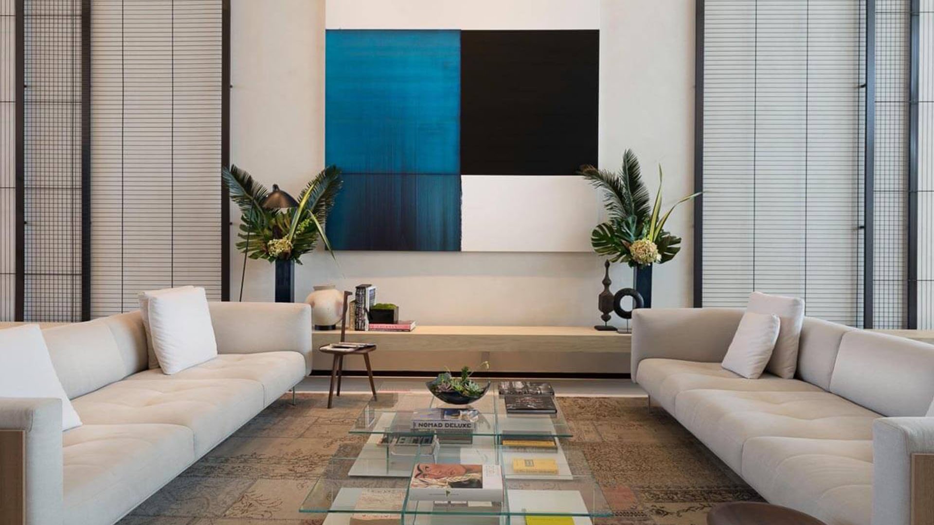 Designer lounge with white sofas, a glass coffee table and blue abstract wall art at Oceana Bal Harbour in Bal Harbour, Florida, presenting a polished luxury gathering space for these ultra luxury condos.