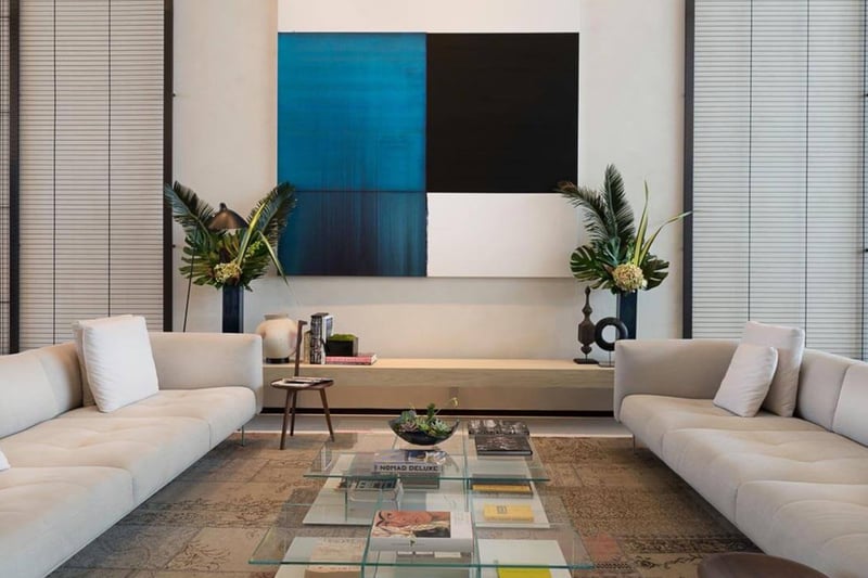 Designer lounge with white sofas, a glass coffee table and blue abstract wall art at Oceana Bal Harbour in Bal Harbour, Florida, presenting a polished luxury gathering space for these ultra luxury condos.