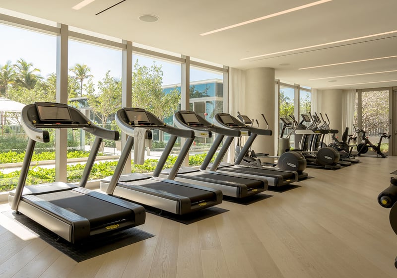 Fitness center with treadmills, cardio equipment and garden facing windows at Oceana Bal Harbour in Bal Harbour, Florida, extending the luxury wellness amenities of these ultra luxury condos.