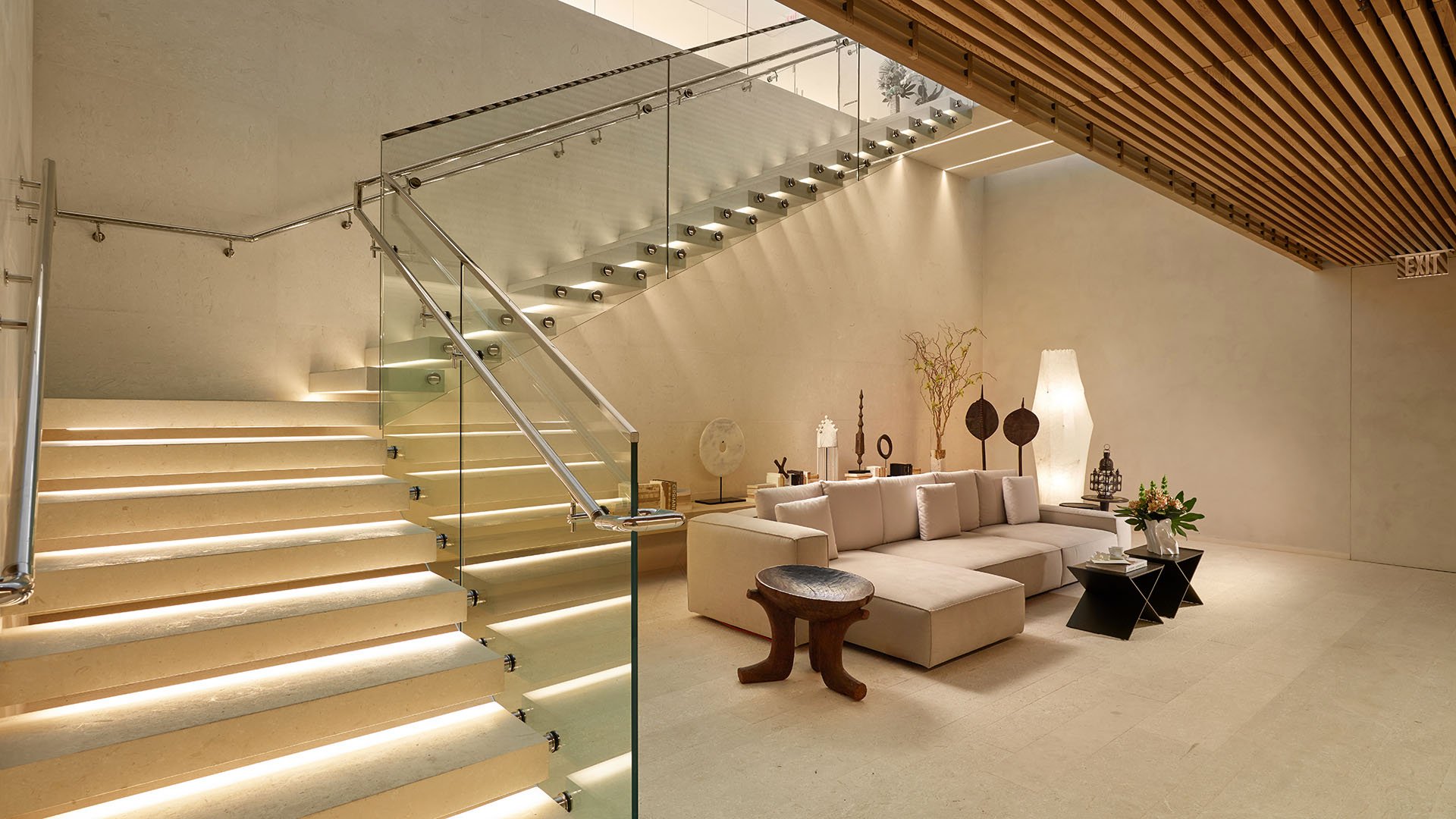 Wide spa lounge with an illuminated glass staircase, sectional seating and warm lighting at Oceana Bal Harbour in Bal Harbour, Florida, elevating the luxury wellness environment of these ultra luxury condos.