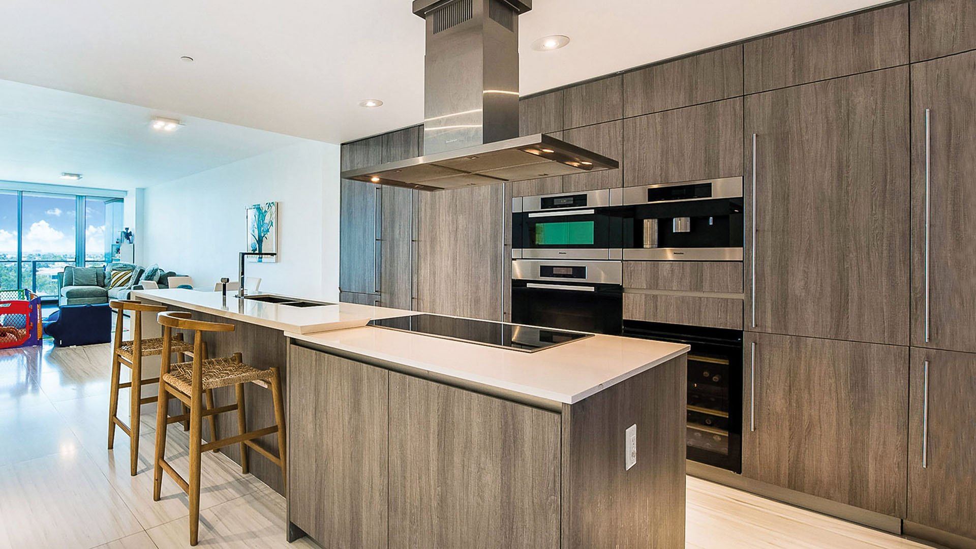 Chef kitchen at Oceana Key Biscayne in Key Biscayne, featuring luxury and ultra luxury condos with a large island, wood cabinetry, integrated appliances, bar seating, and an open layout.