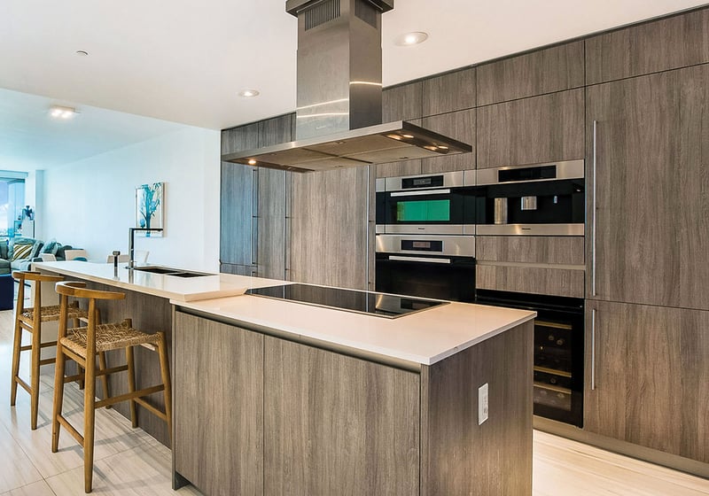 Chef kitchen at Oceana Key Biscayne in Key Biscayne, featuring luxury and ultra luxury condos with a large island, wood cabinetry, integrated appliances, bar seating, and an open layout.