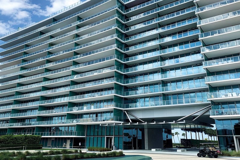 Street-level exterior of Oceana Key Biscayne in Key Biscayne, highlighting luxury and ultra luxury condos with curving glass balconies, a sleek coastal facade, and landscaped arrival areas.
