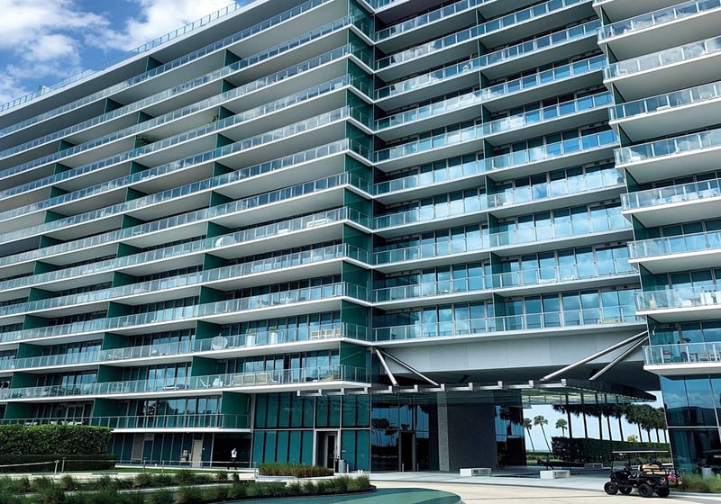 Street-level exterior of Oceana Key Biscayne in Key Biscayne, highlighting luxury and ultra luxury condos with curving glass balconies, a sleek coastal facade, and landscaped arrival areas.