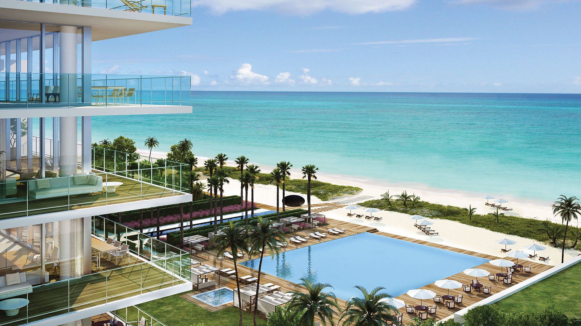 Elevated waterfront view at Oceana Key Biscayne in Key Biscayne, showing luxury and ultra luxury condos above a resort pool deck, palm trees, white sand beach, and bright turquoise ocean.