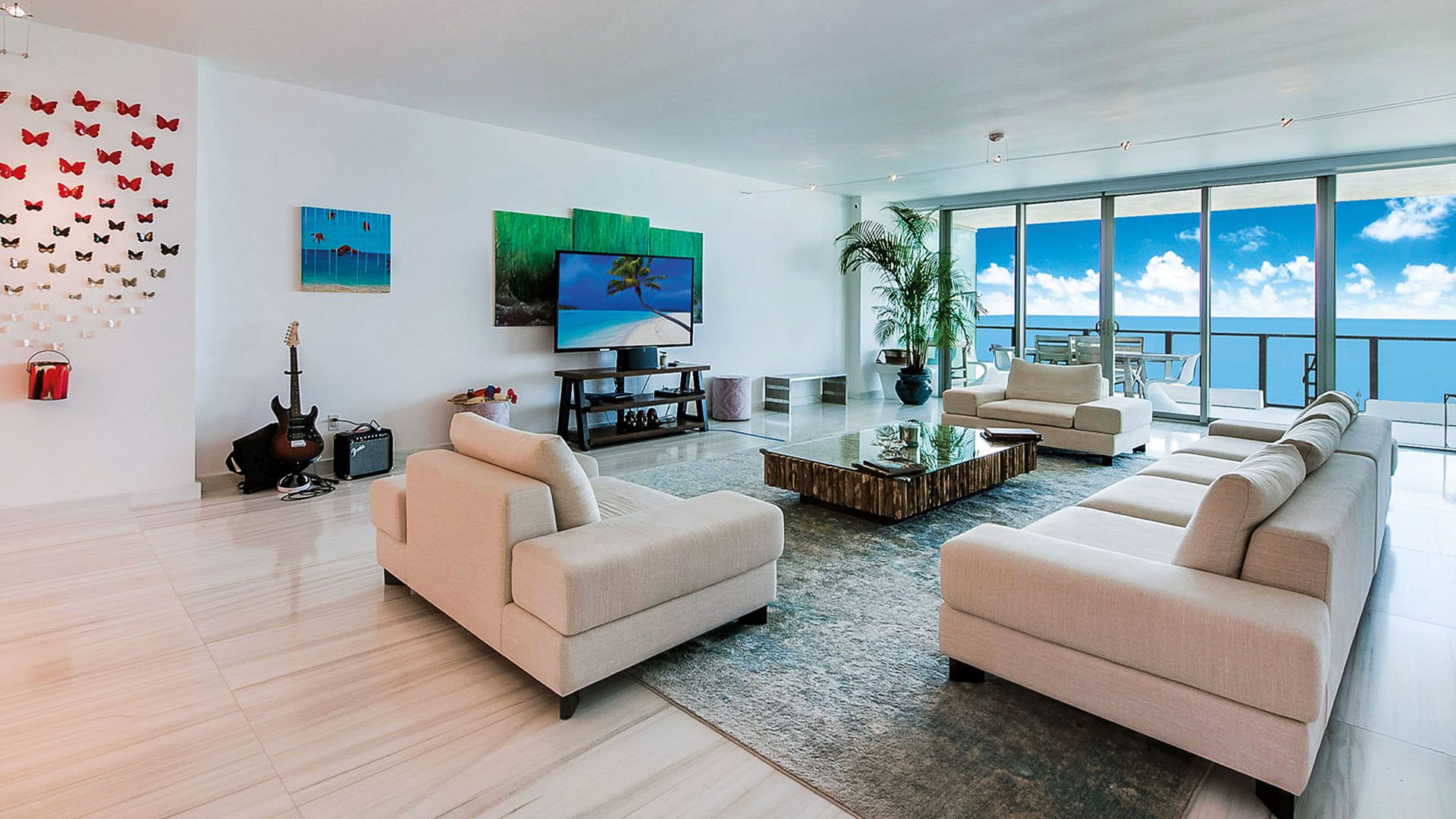 Oceanfront living room at Oceana Key Biscayne in Key Biscayne, highlighting luxury and ultra luxury condos with expansive seating, large art pieces, glossy floors, and a balcony facing the water.