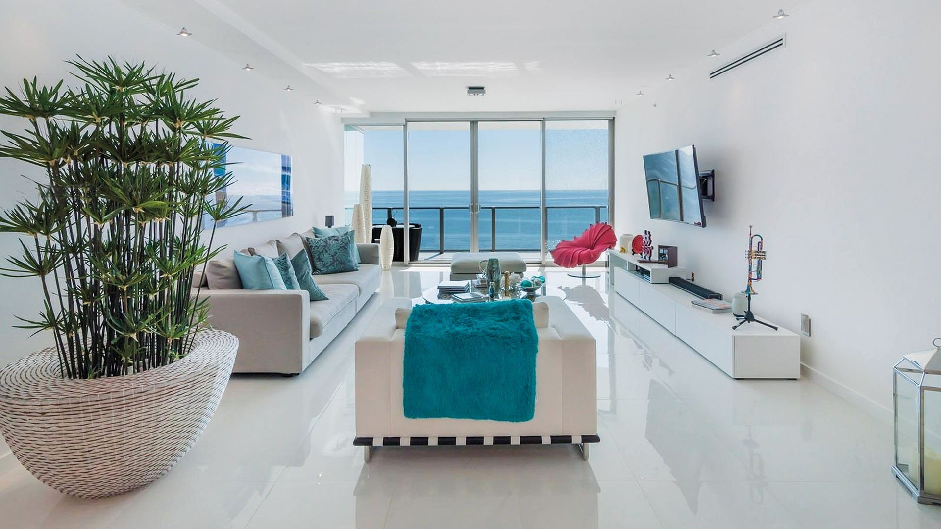 White ocean-view living room at Oceana Key Biscayne in Key Biscayne, highlighting luxury and ultra luxury condos with glossy floors, bright seating, modern decor, and a balcony overlooking the water.