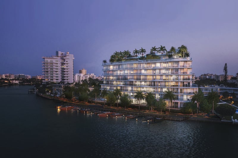 Night waterfront exterior of Onda, Bay Harbor Islands, Miami, Florida, with illuminated marina docks and rooftop palms, showcasing luxury and ultra luxury preconstruction waterfront condos on the bay.