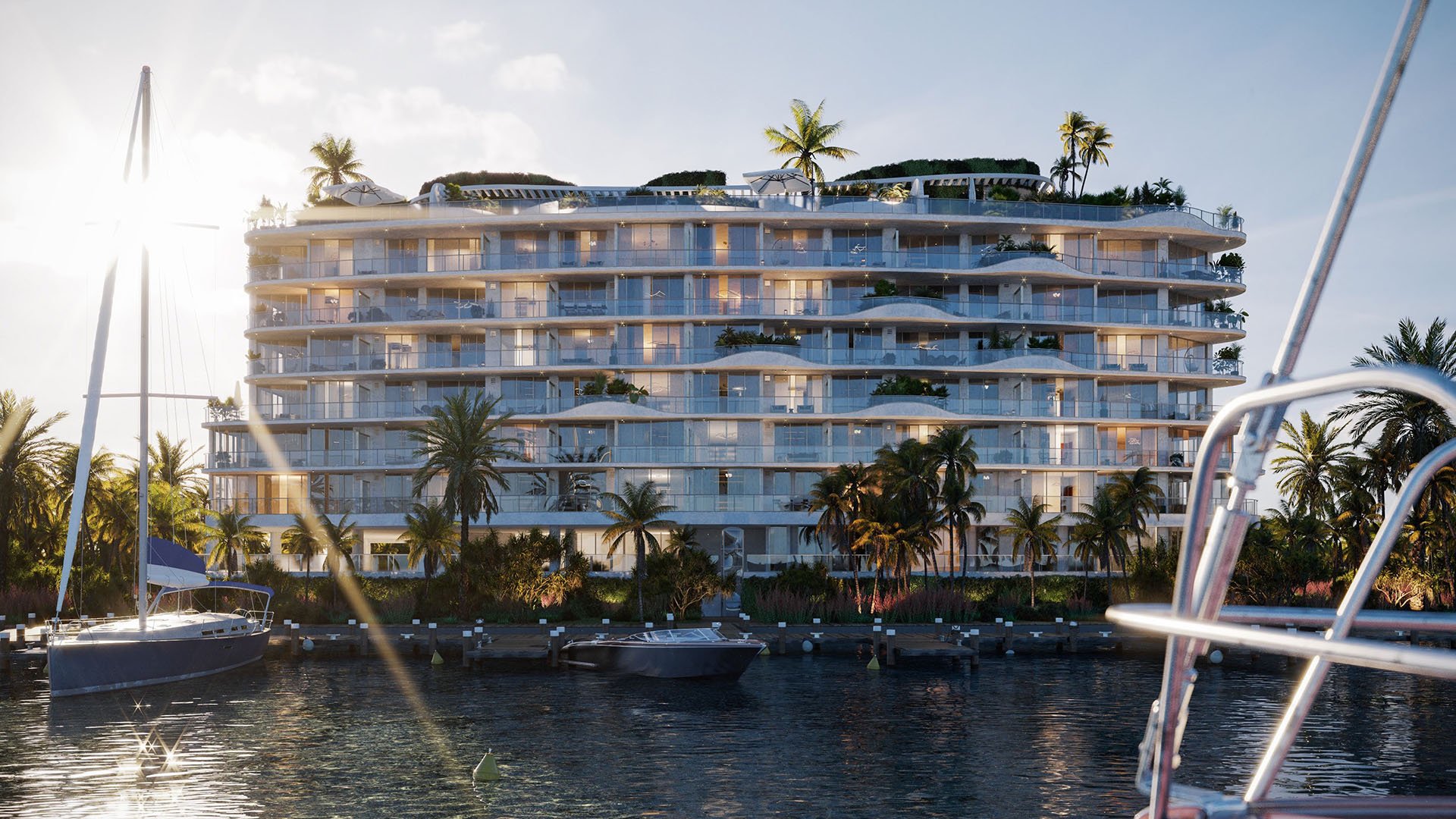 Sunset waterfront view of Onda, Bay Harbor Islands, Miami, Florida, with marina boats and palm-lined shoreline, showcasing luxury and ultra luxury preconstruction condos in a boutique condominium setting.