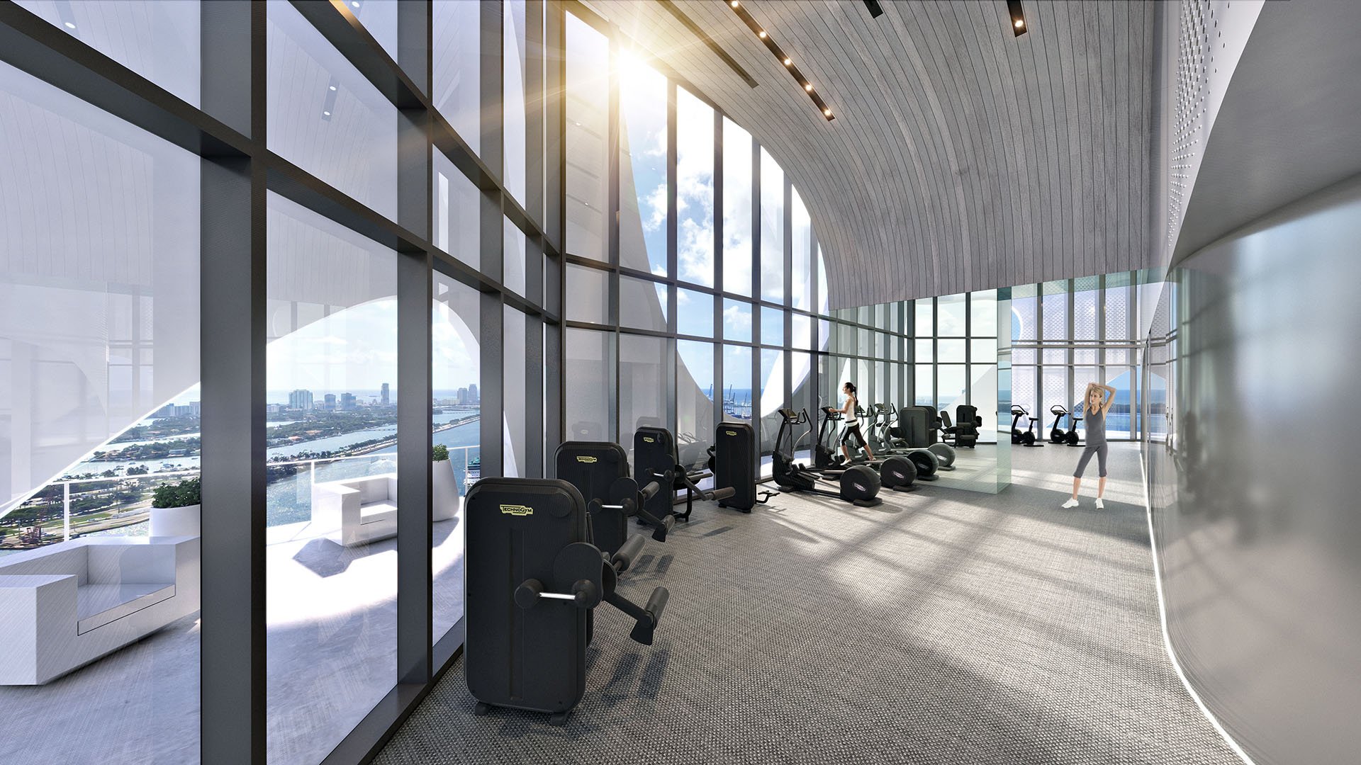 Fitness center at One Thousand Museum in Downtown Miami with floor-to-ceiling glass, cardio equipment, and broad water views for luxury and ultra luxury condos.