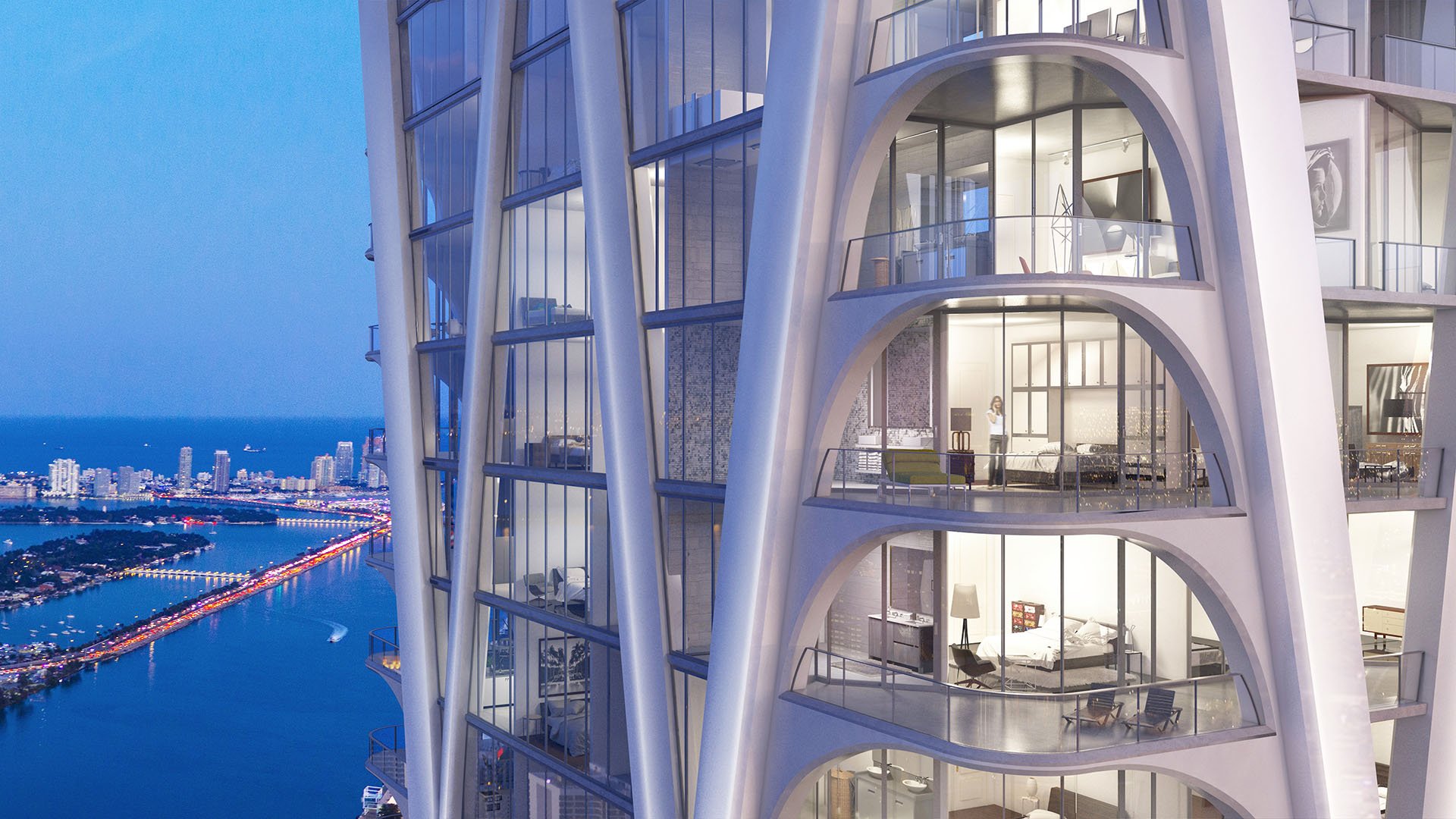 Mid-level facade view of One Thousand Museum in Downtown Miami with illuminated residences and water beyond, highlighting luxury and ultra luxury condos.