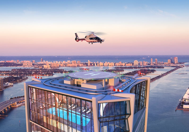 Rooftop helipad and pool at One Thousand Museum in Downtown Miami with a helicopter above the waterfront at sunset, serving luxury and ultra luxury condos.