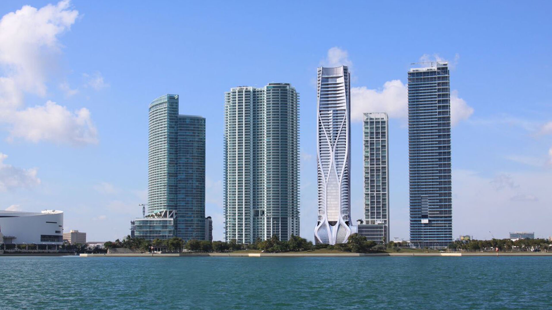Waterfront view of One Thousand Museum in Downtown Miami rising across the bay among neighboring towers, highlighting luxury and ultra luxury condos.